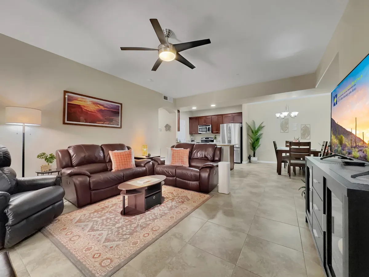 This photo focuses on the living area, featuring leather sofas, a coffee table, a television, and a view of the adjacent dining area. The arrangement invites relaxation, entertainment, and group activities, aligning with the section’s emphasis on comfort and togetherness.