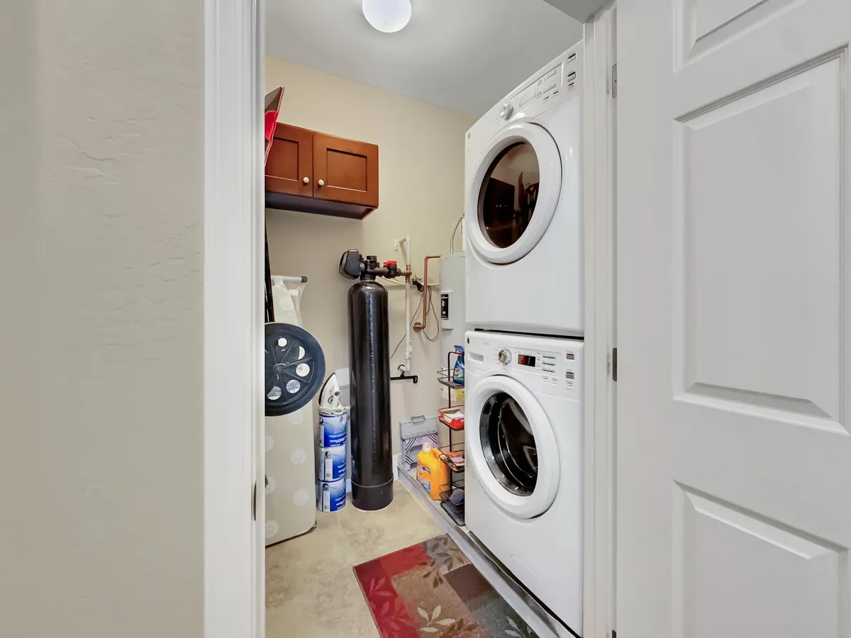 This image displays a stacked washer and dryer paired with storage cabinets and laundry supplies, highlighting the practical, home-like amenities provided. It reflects the ease and efficiency of having in-unit laundry, supporting a worry-free extended stay.