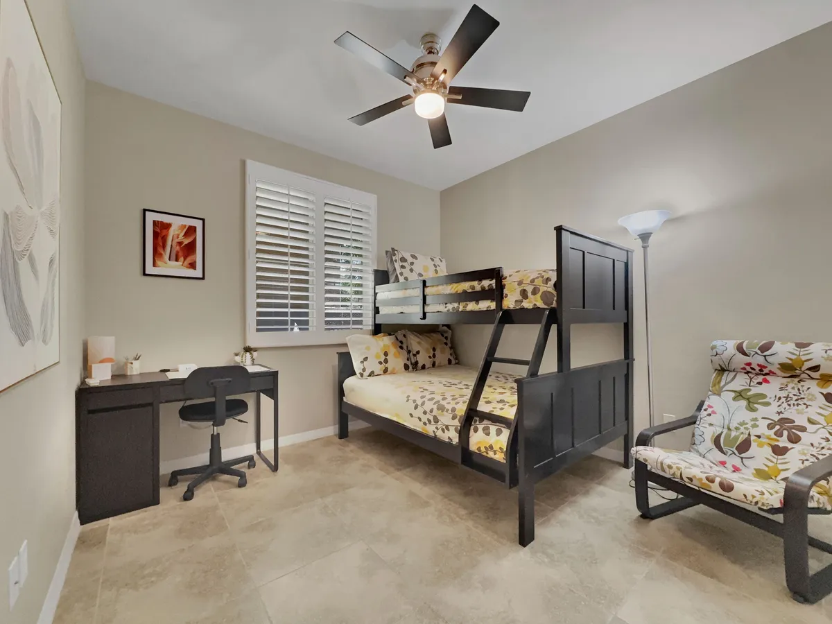 A playful and functional bunk bedroom equipped with a bunk bed, a study desk with a floral chair, and cheerful wall art. The room’s layout encourages both sleep and creative activities, making it perfect for children or groups.