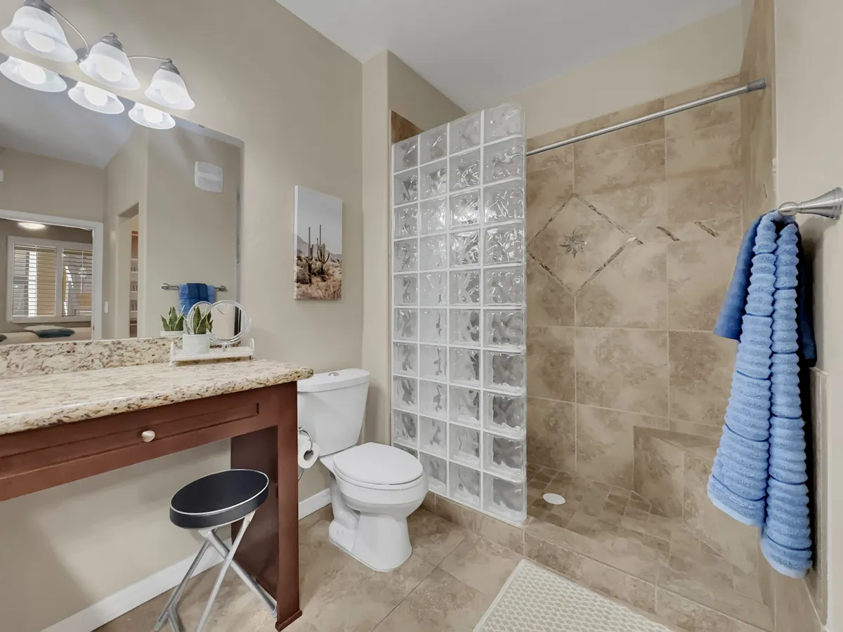 A modern bathroom featuring a granite countertop, a large glass block shower, and contemporary lighting. The serene, inviting atmosphere suggests a space for refreshing showers and peaceful self-care routines.