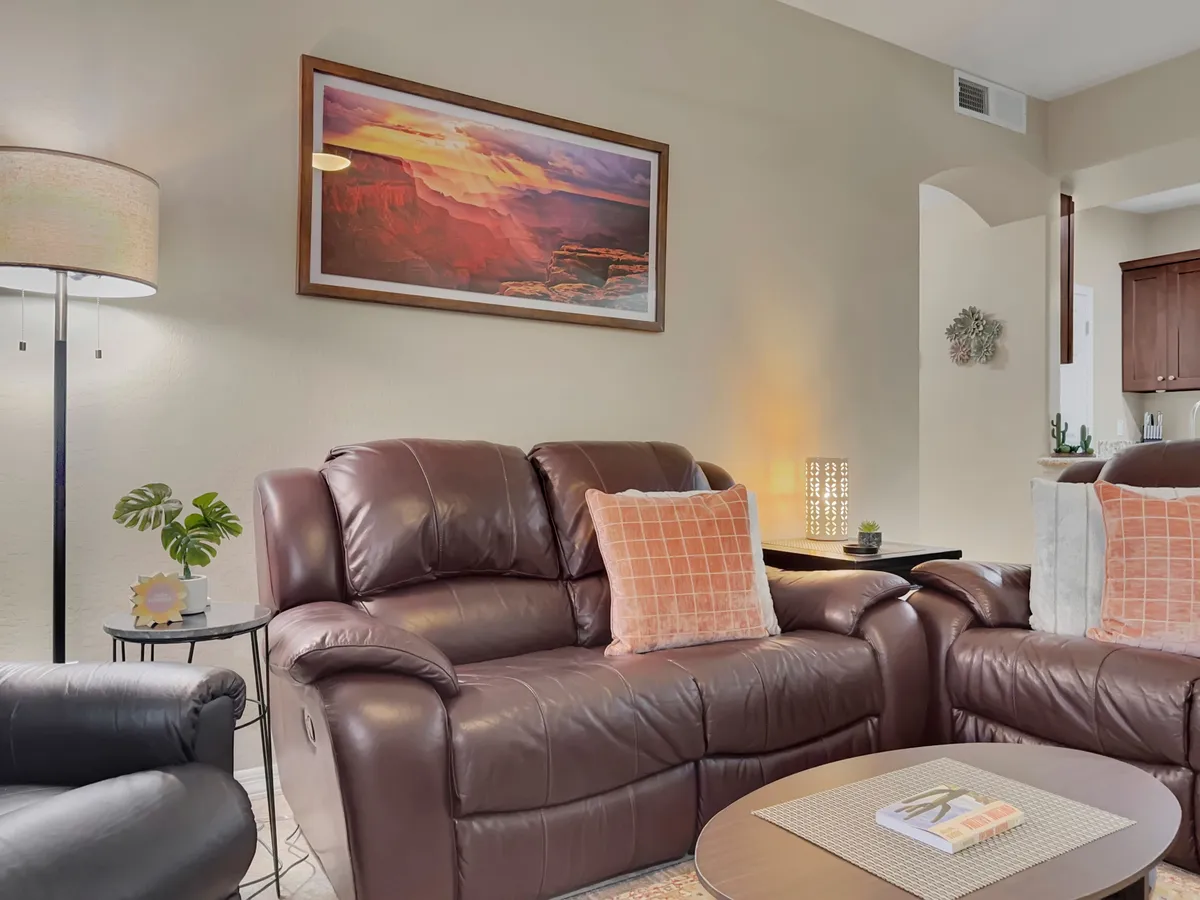 A cozy seating area with plush leather sofas, a stylish coffee table, framed artwork, and a soft table lamp. The arrangement suggests a comfortable environment for socializing and group conversations, perfect for post-event gatherings.