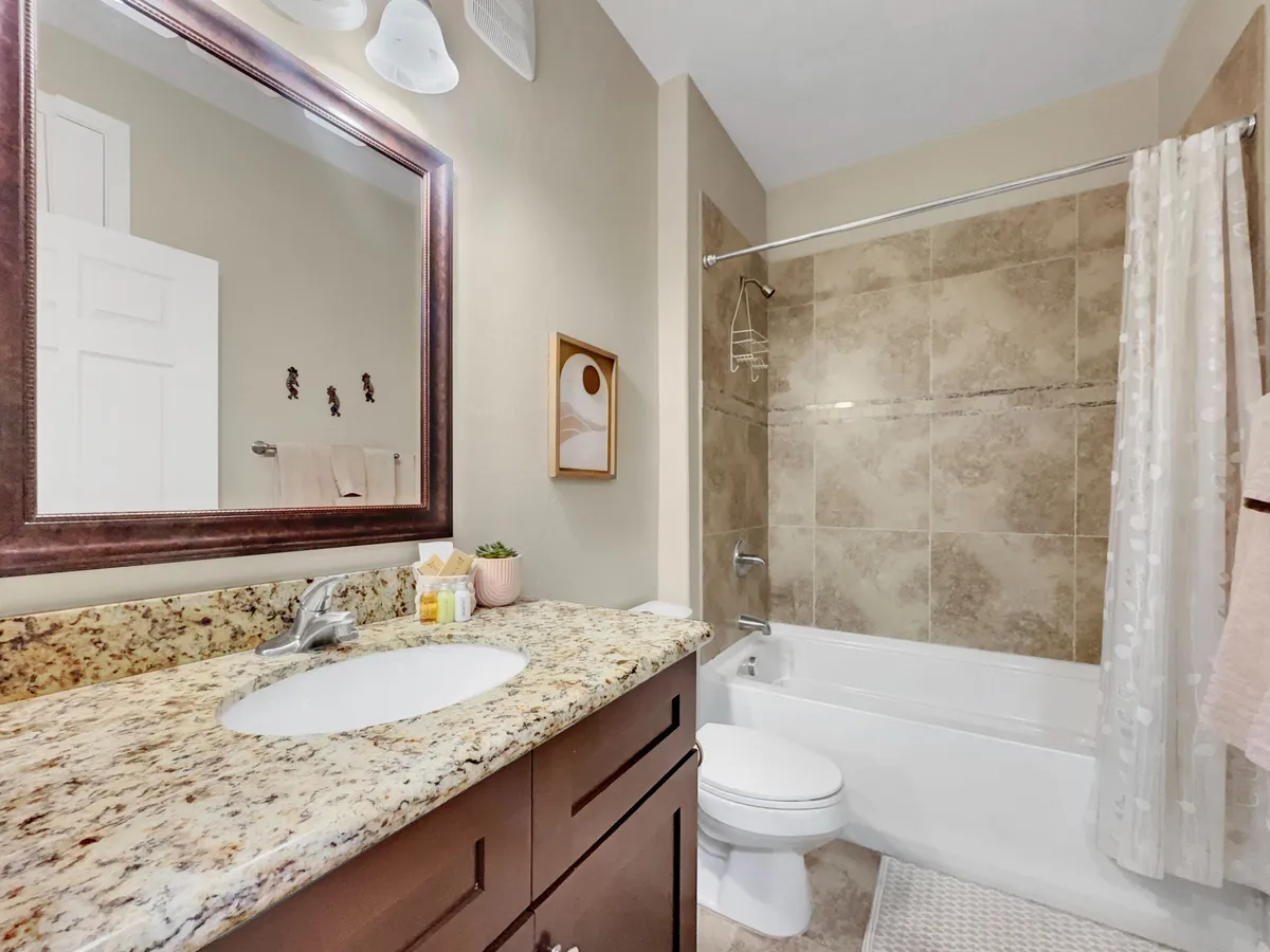 A calming bathroom space featuring a luxurious bathtub, granite countertop, stylish mirror, decorative wall art, and lush green plants, evoking a spa-like ambiance perfect for relaxation after a day outdoors.