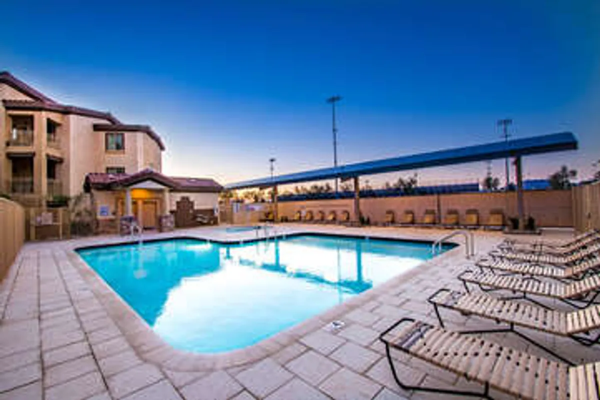 An inviting swimming pool framed by lounge chairs and the facade of the community building, radiating a welcoming, vacation-like vibe. The scene suggests opportunities for both sunbathing and social gatherings.