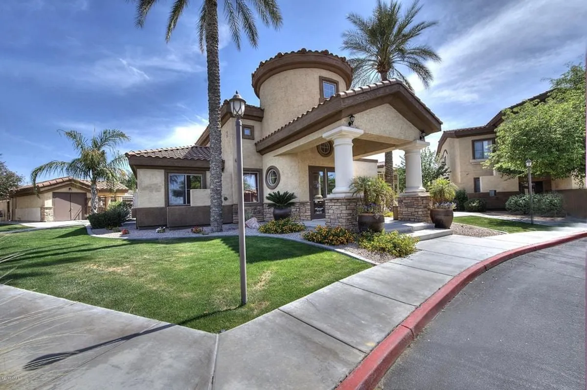 This image shows an inviting exterior with tall palm trees, an arched entrance, decorative columns, and a landscaped garden. The space looks ready for gatherings, whether for relaxing outdoors or hosting a get-together.