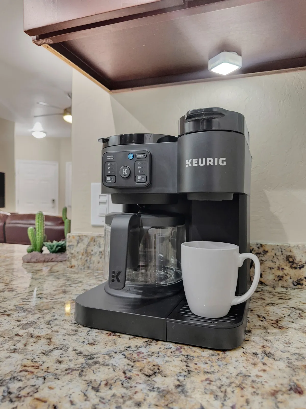 The image showcases a Keurig coffee maker, a white coffee mug, and a granite countertop, all set in a well-lit, welcoming kitchen space. This spot encourages morning rituals and slow, comfortable starts to the day—perfect for extended stays where guests can settle into a homey routine.