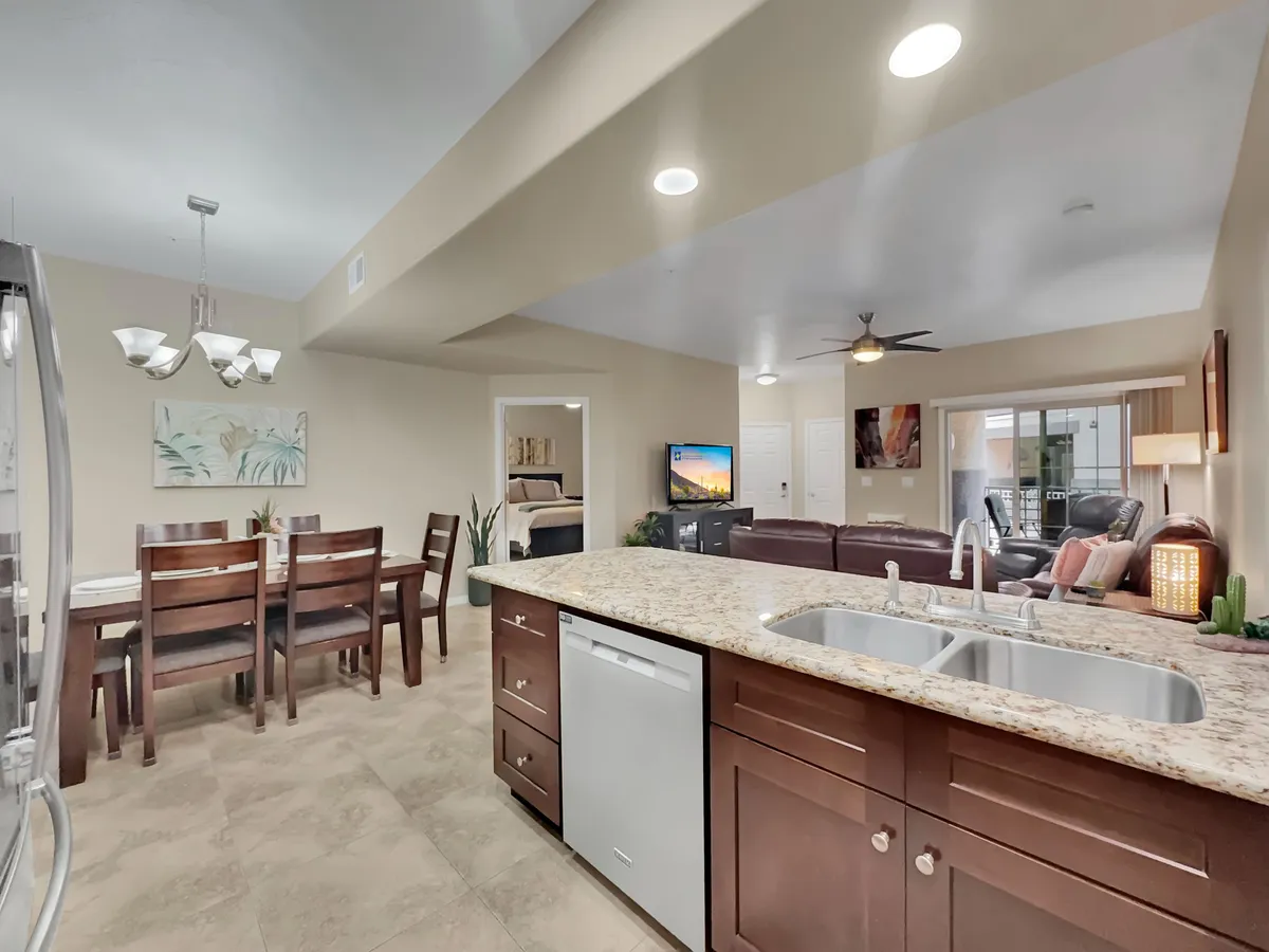 This image presents a cohesive view of the open-concept living, dining, and kitchen area. The granite countertop, dining table, living room area, and kitchen appliances are all visible, illustrating how these spaces flow together. The inviting and functional atmosphere is emphasized by the comfortable seating and thoughtfully arranged decor.